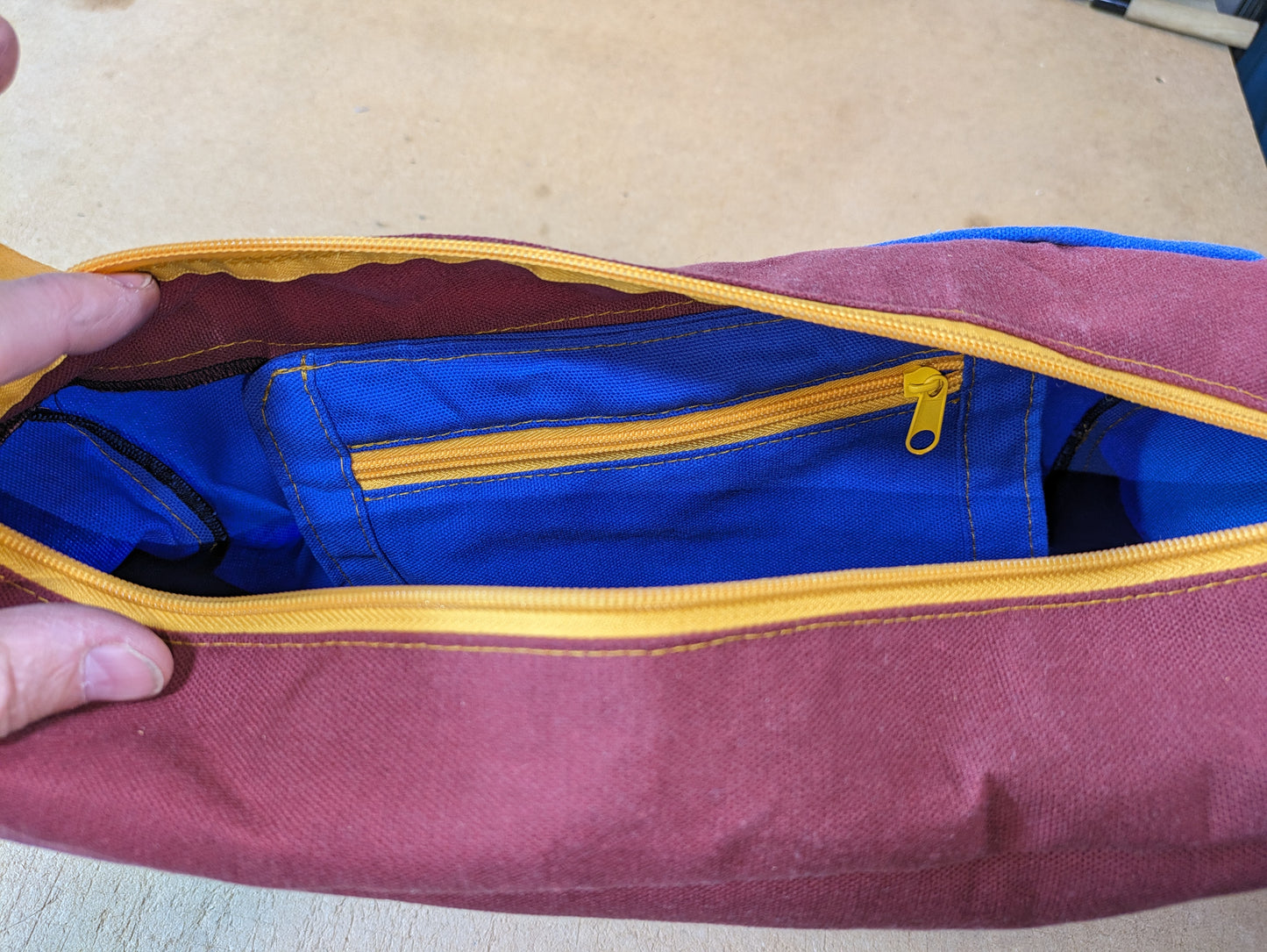 Shoulder bag in burgundy and blue with yellow zippers and strap