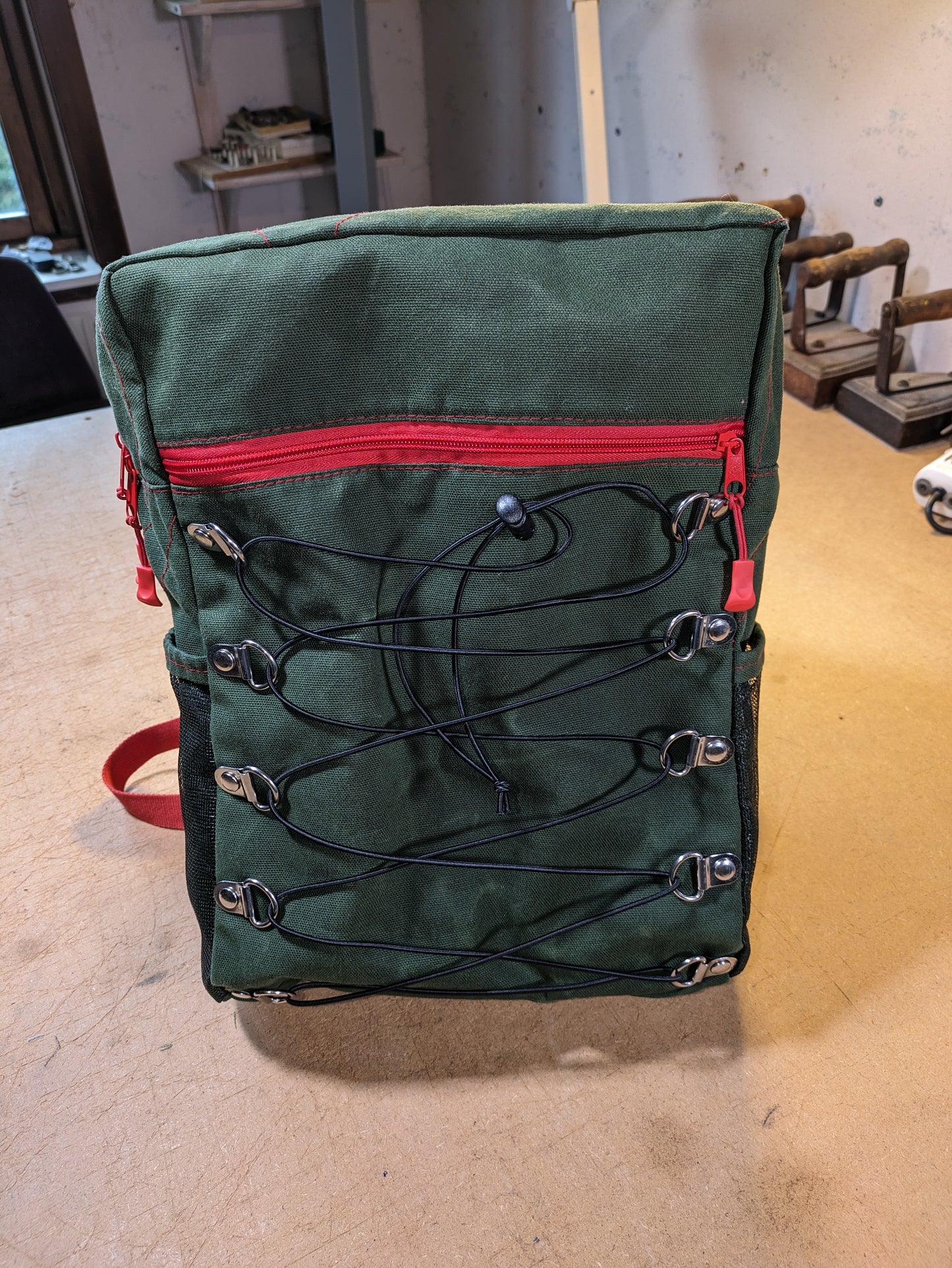 Backpack in green with red zippers, thread and straps