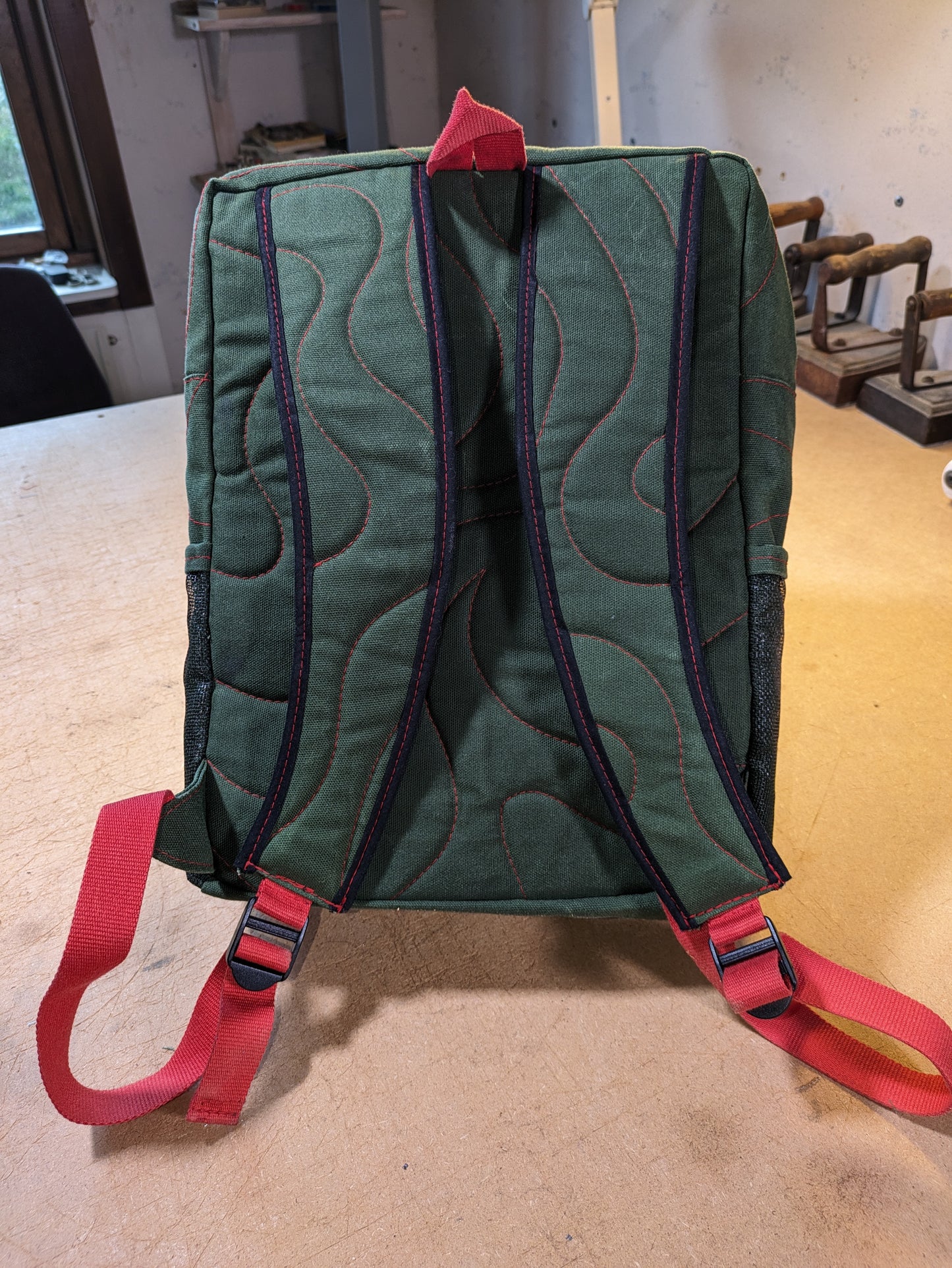 Backpack in green with red zippers, thread and straps