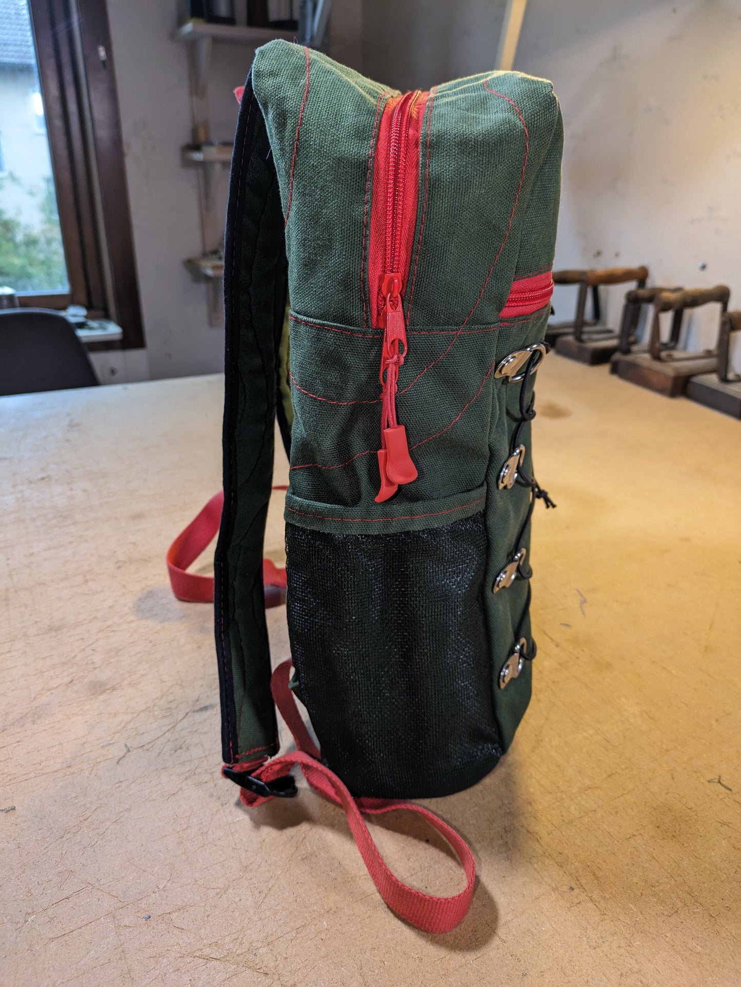 Backpack in green with red zippers, thread and straps