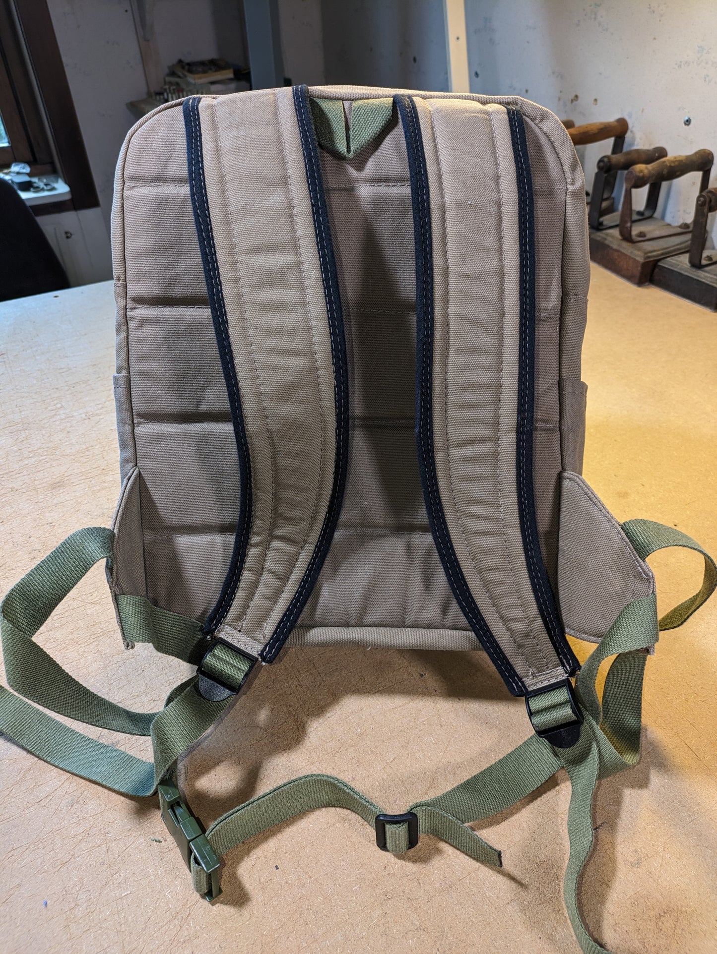 Khaki backpack with matching zippers, wire, black straps and flexcord