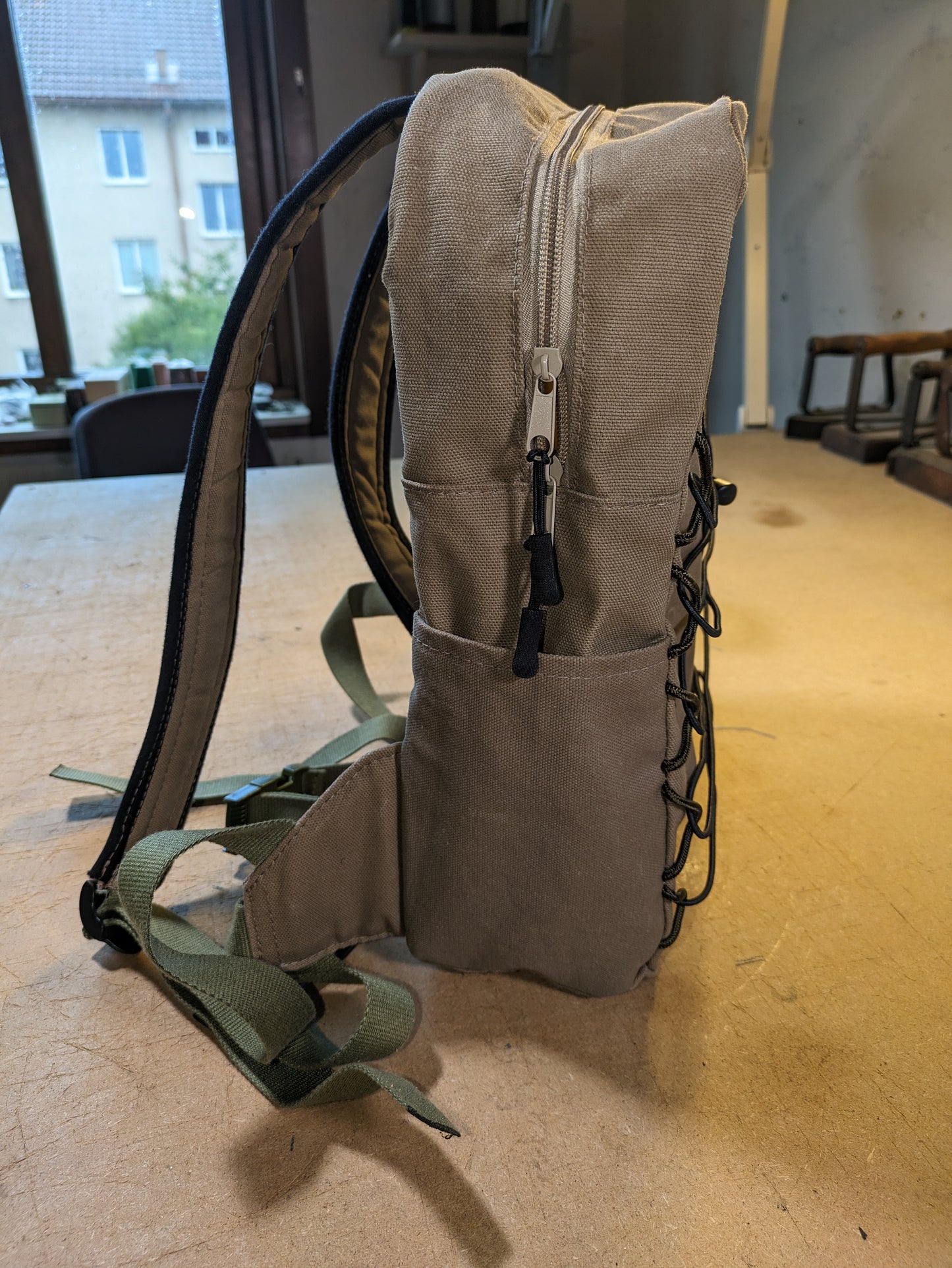 Khaki backpack with matching zippers, wire, black straps and flexcord