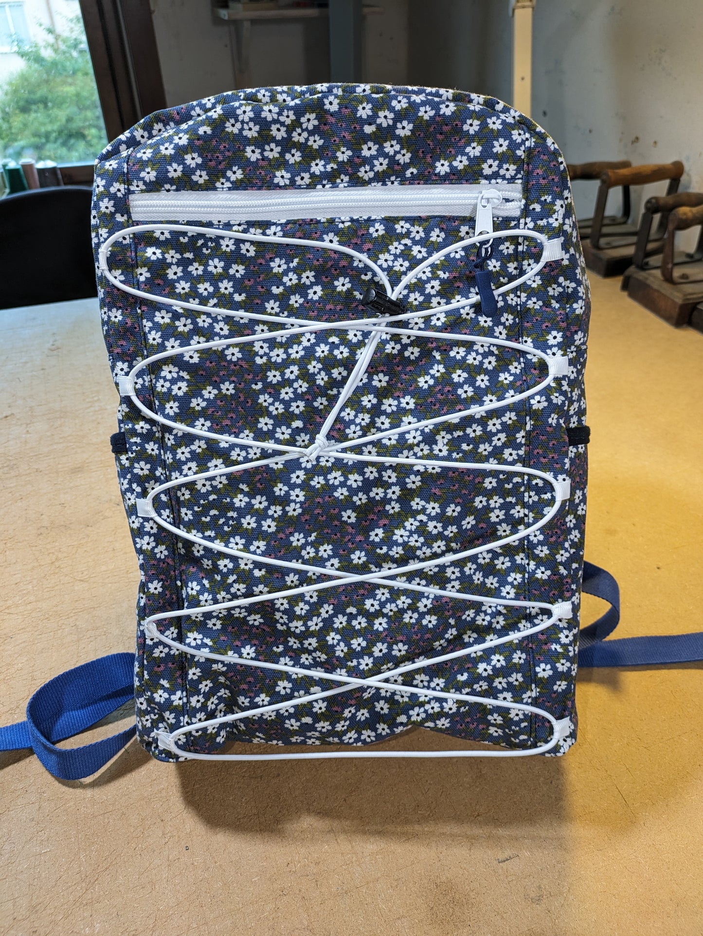 Blue backpack with floral pattern and white zippers