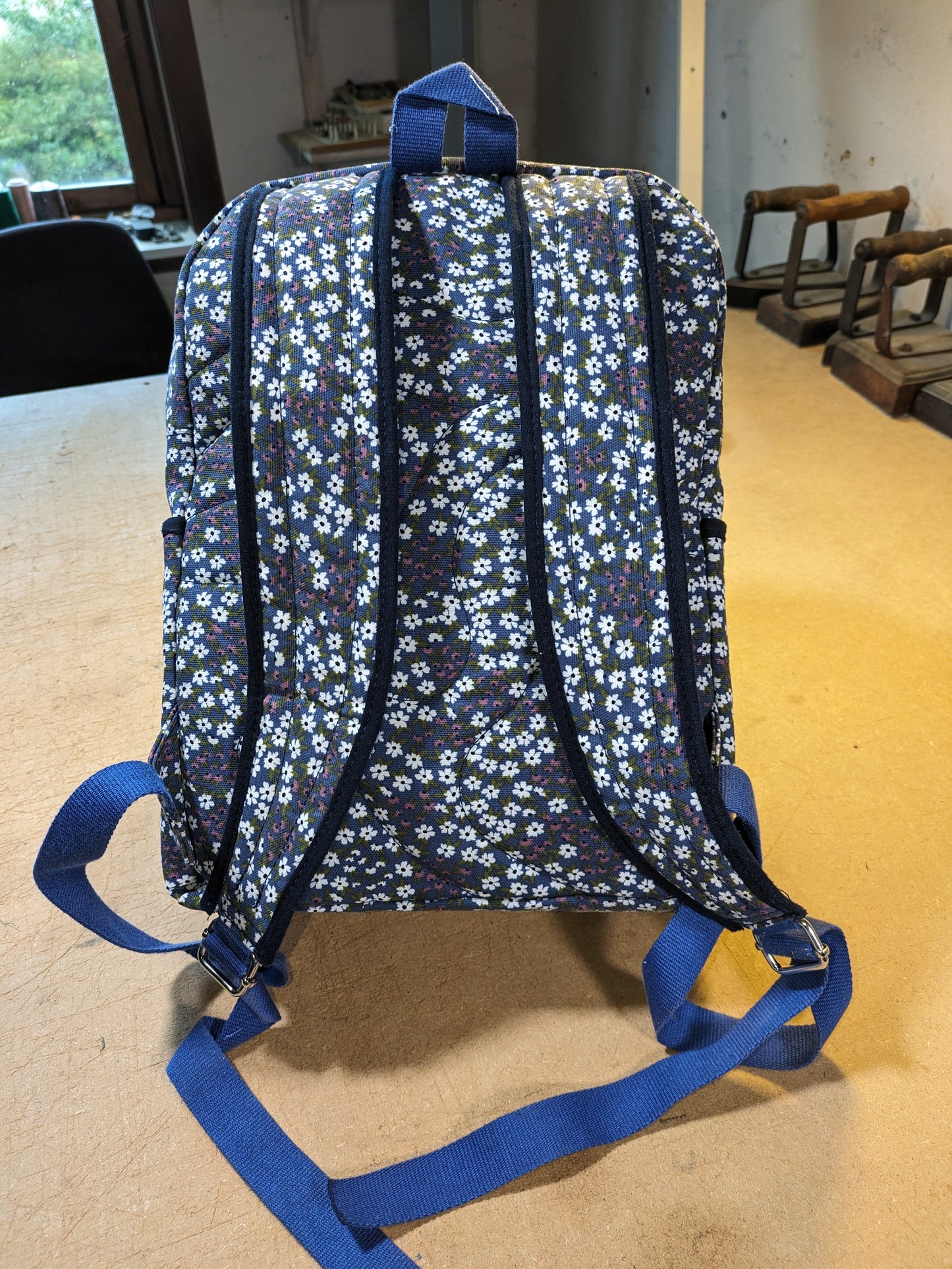 Blue backpack with floral pattern and white zippers