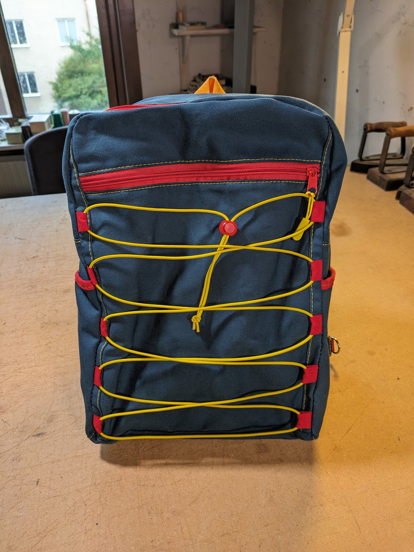 Petrol/blue backpack with red zippers, yellow thread, red and yellow straps and flexcord