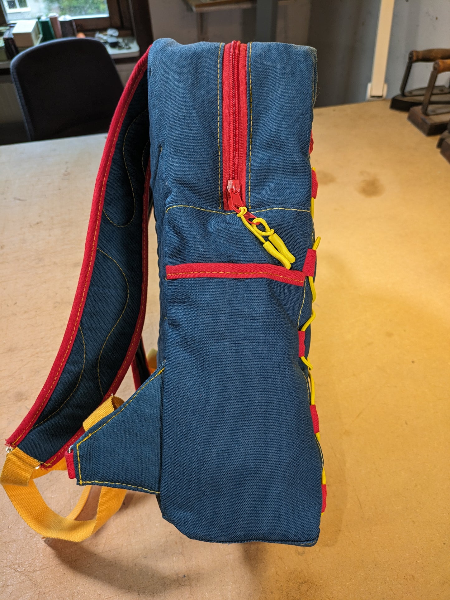 Petrol/blue backpack with red zippers, yellow thread, red and yellow straps and flexcord