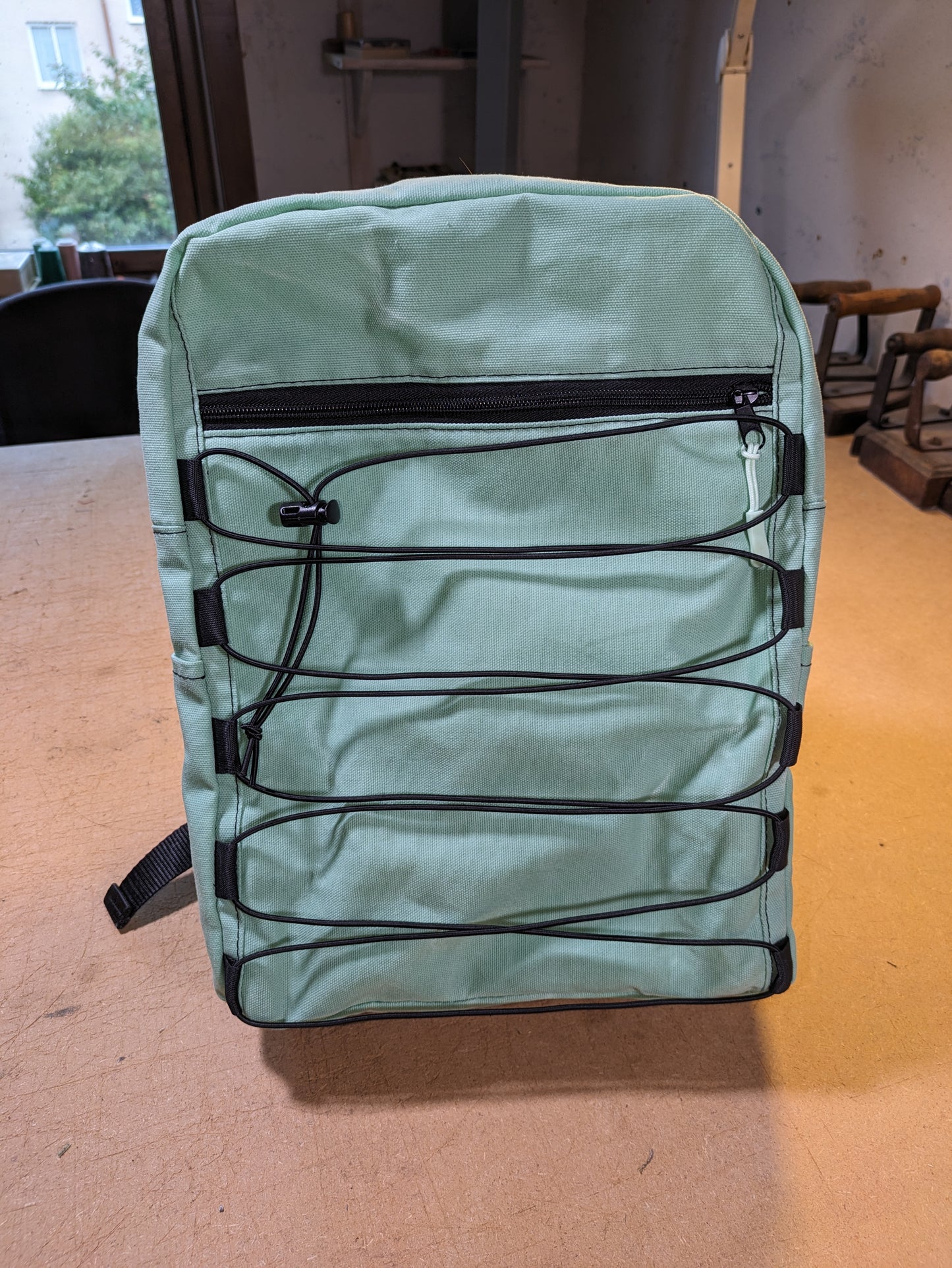 Mint green backpack with black zippers, wire, straps and flexcord