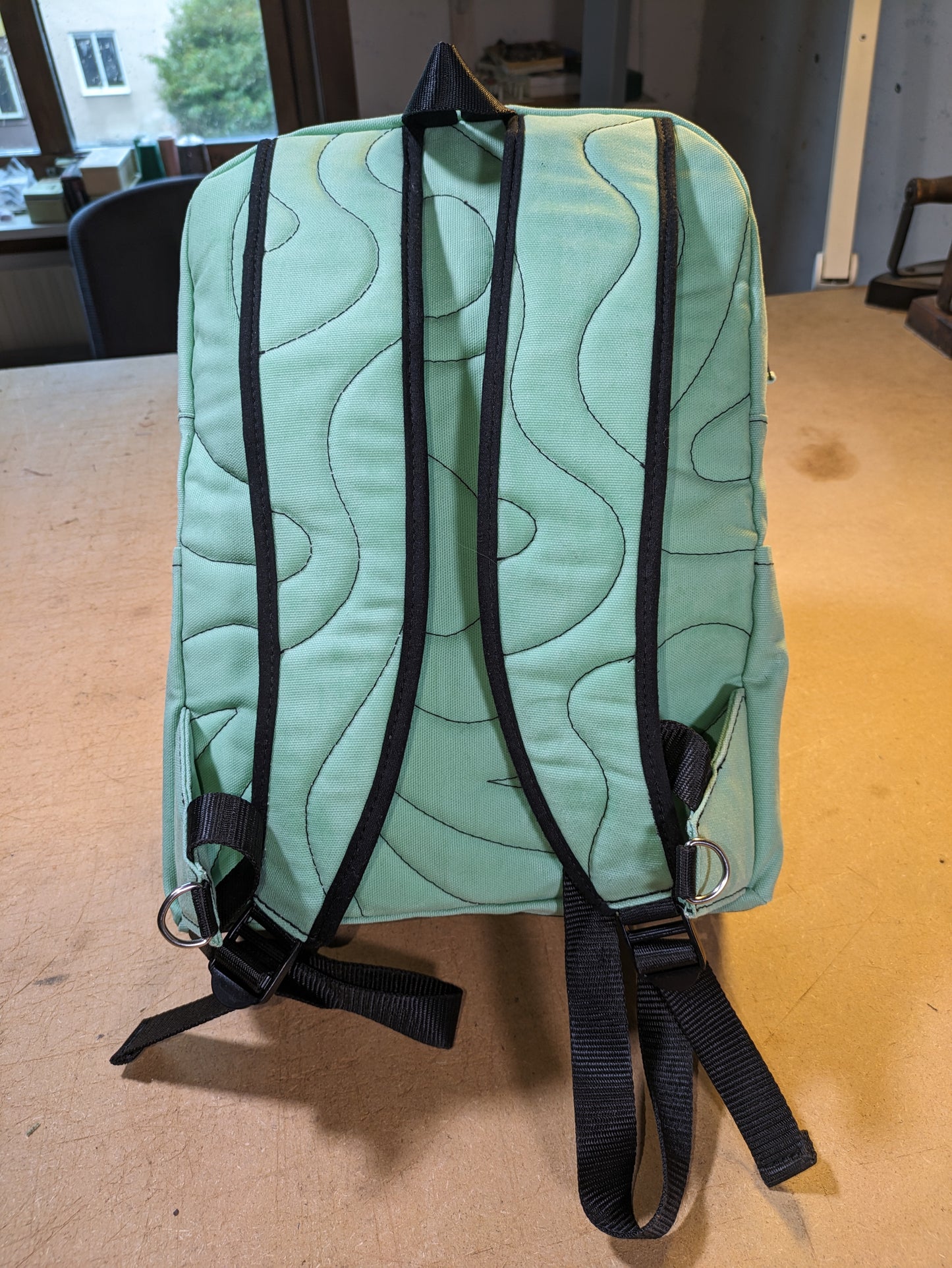 Mint green backpack with black zippers, wire, straps and flexcord