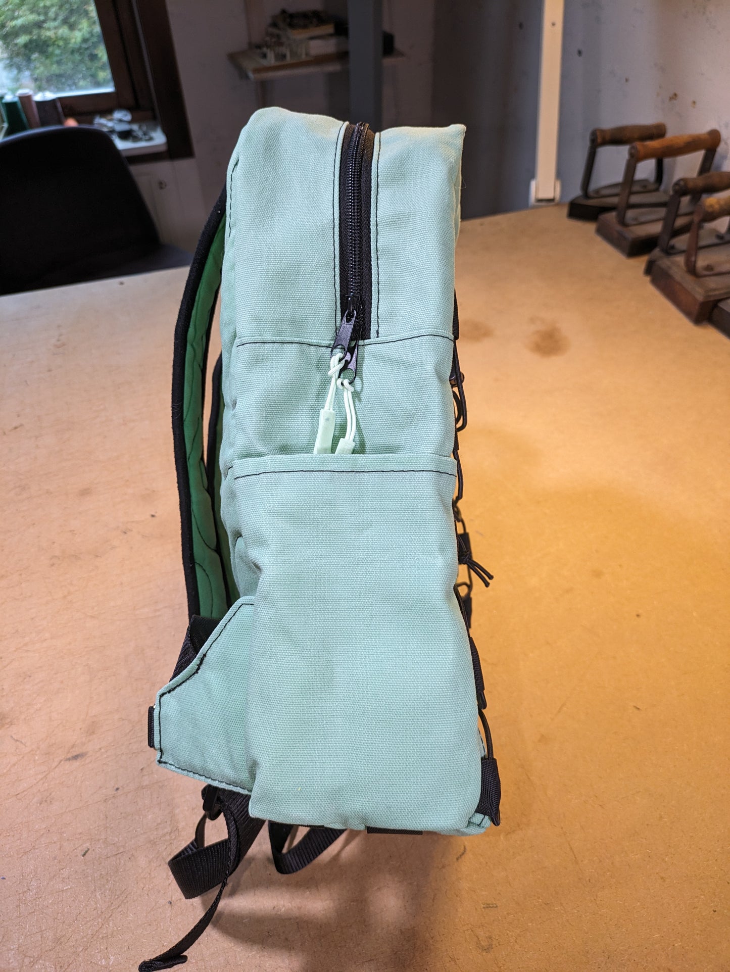 Mint green backpack with black zippers, wire, straps and flexcord