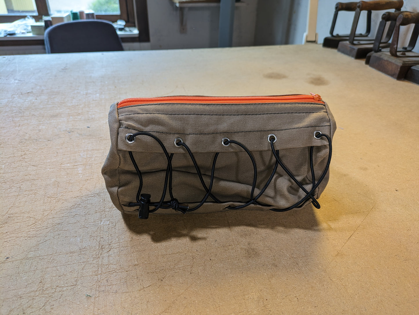 Drab/Khaki handlebar bag with black webbing, orange zipper and flexcord