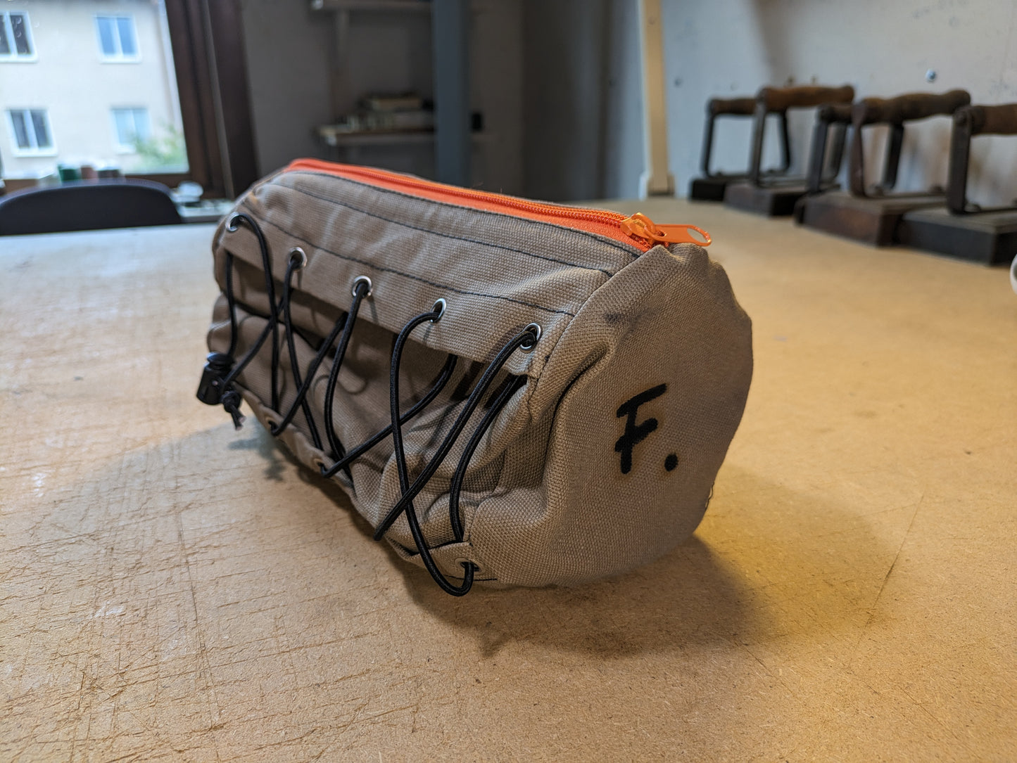 Drab/Khaki handlebar bag with black webbing, orange zipper and flexcord