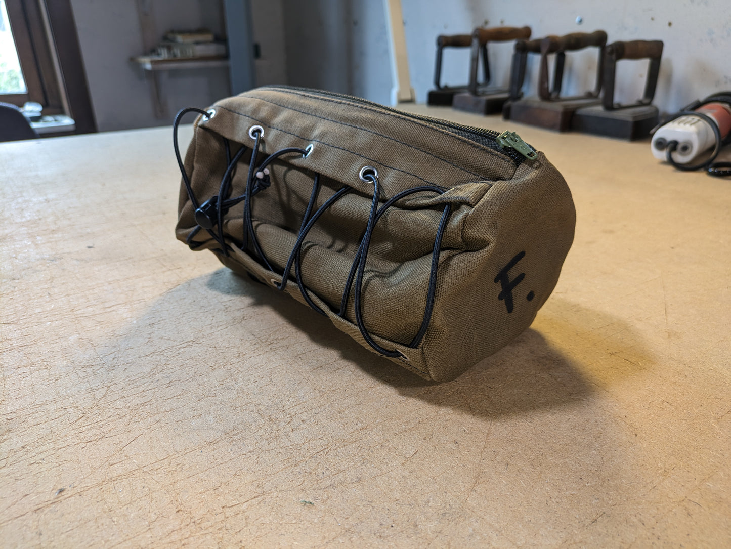 Drab/Khaki handlebar bag with black webbing, green zipper and flexcord