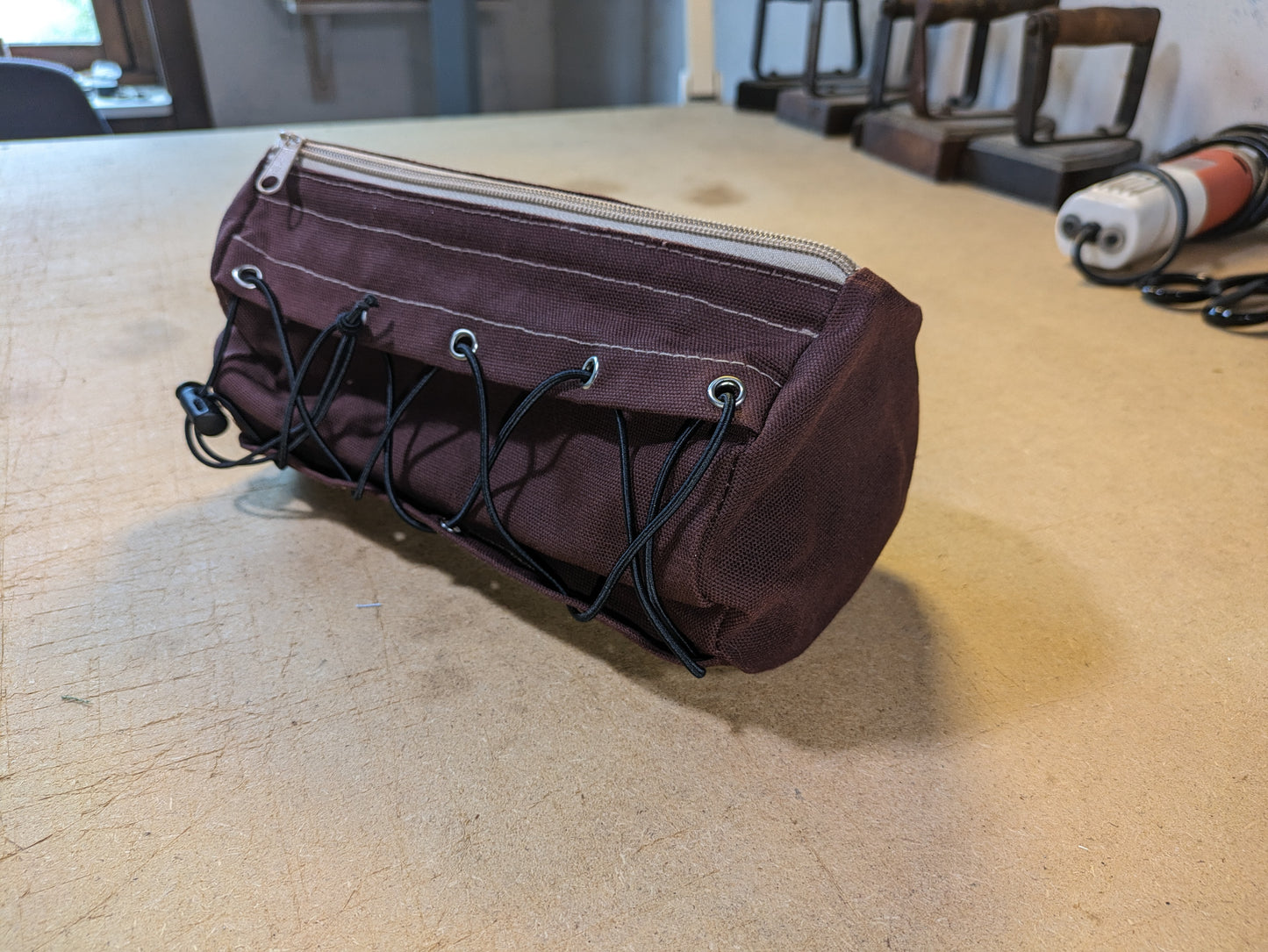 Burgundy handlebar bag with beige webbing and flexcord