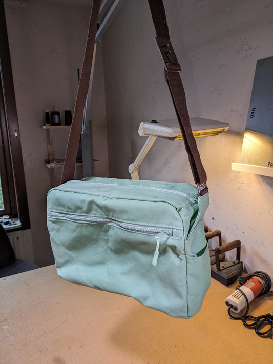 Shoulder bag in mint green with matching zippers and brown strap