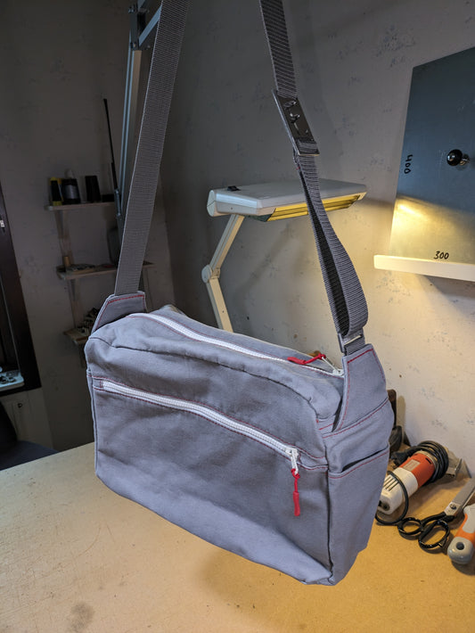 Shoulder bag in gray with white zippers, red thread and gray strap