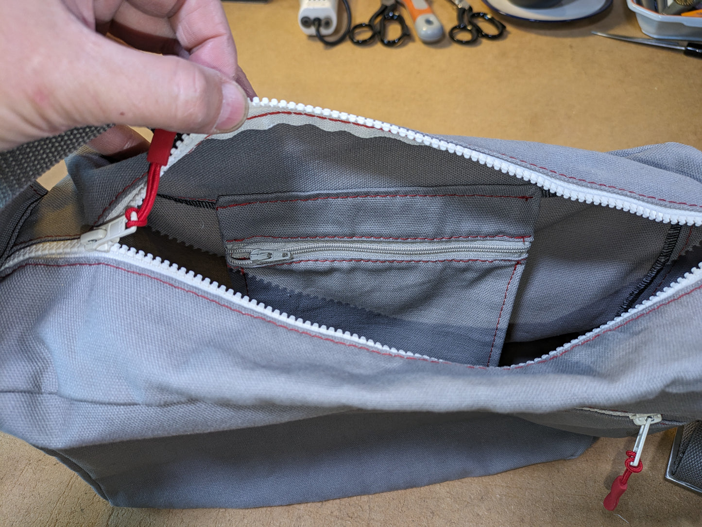 Shoulder bag in gray with white zippers, red thread and gray strap